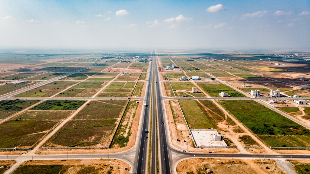 Aerial-style regional overview of Dholera with roads, land, and open horizon